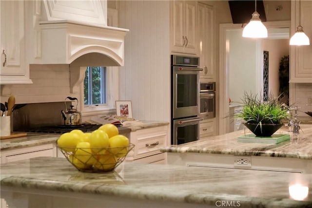 kitchen featuring premium range hood, decorative light fixtures, light stone counters, decorative backsplash, and stainless steel double oven