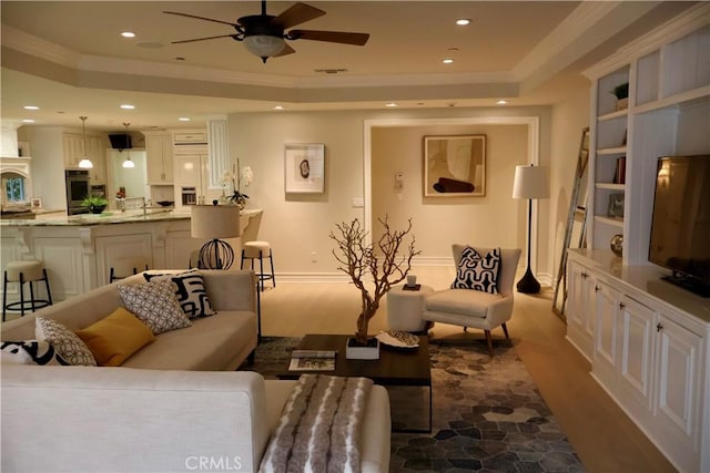 living room with visible vents, ornamental molding, a ceiling fan, a tray ceiling, and recessed lighting