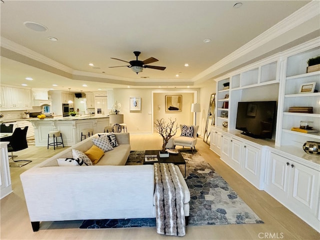 living area with recessed lighting, a raised ceiling, ornamental molding, and a ceiling fan