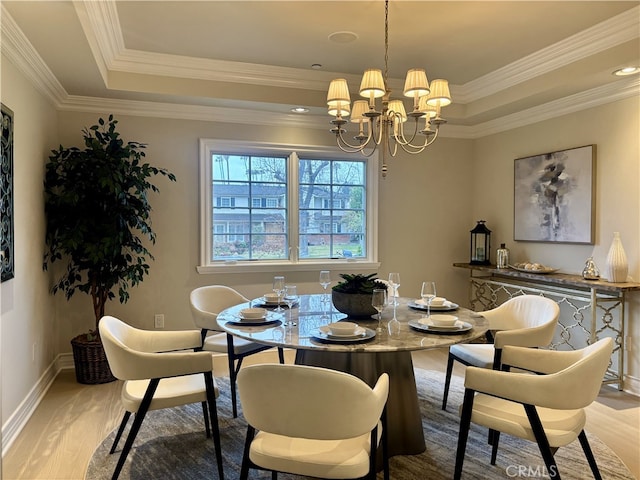 dining room with a notable chandelier, crown molding, light wood-type flooring, and a tray ceiling