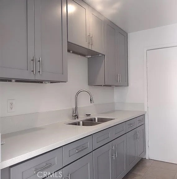 kitchen featuring a sink, light tile patterned floors, gray cabinets, and light countertops