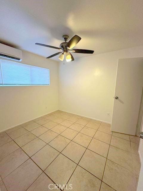 empty room featuring light tile patterned floors, a ceiling fan, and a wall unit AC