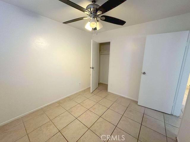 unfurnished bedroom with light tile patterned floors, a ceiling fan, a closet, and baseboards