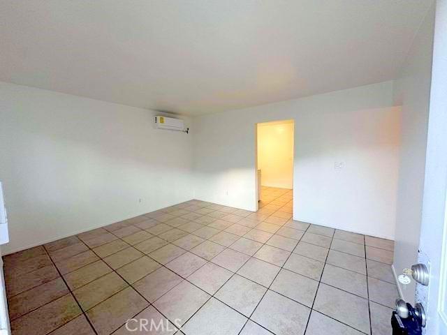 spare room with light tile patterned floors and a wall mounted air conditioner