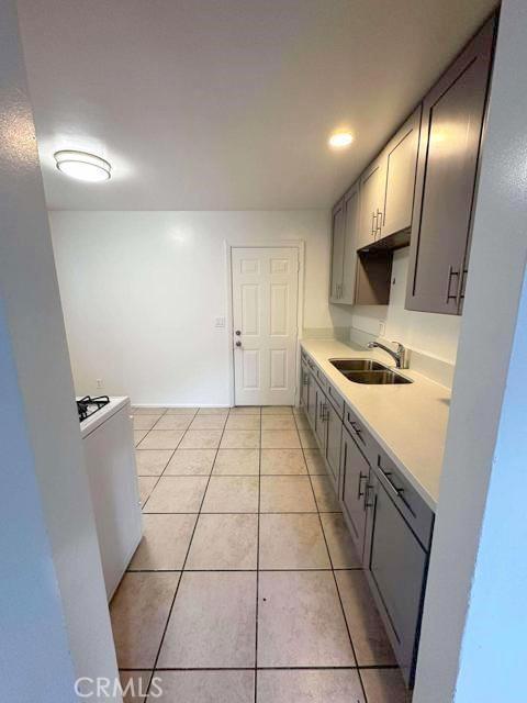 kitchen featuring a sink, gray cabinets, light countertops, and light tile patterned floors