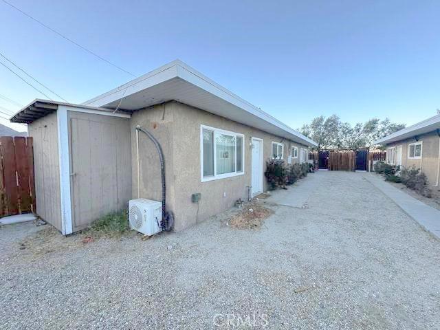 view of side of home featuring ac unit, fence, and stucco siding