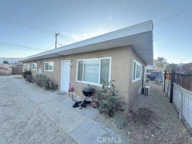 exterior space featuring stucco siding and fence