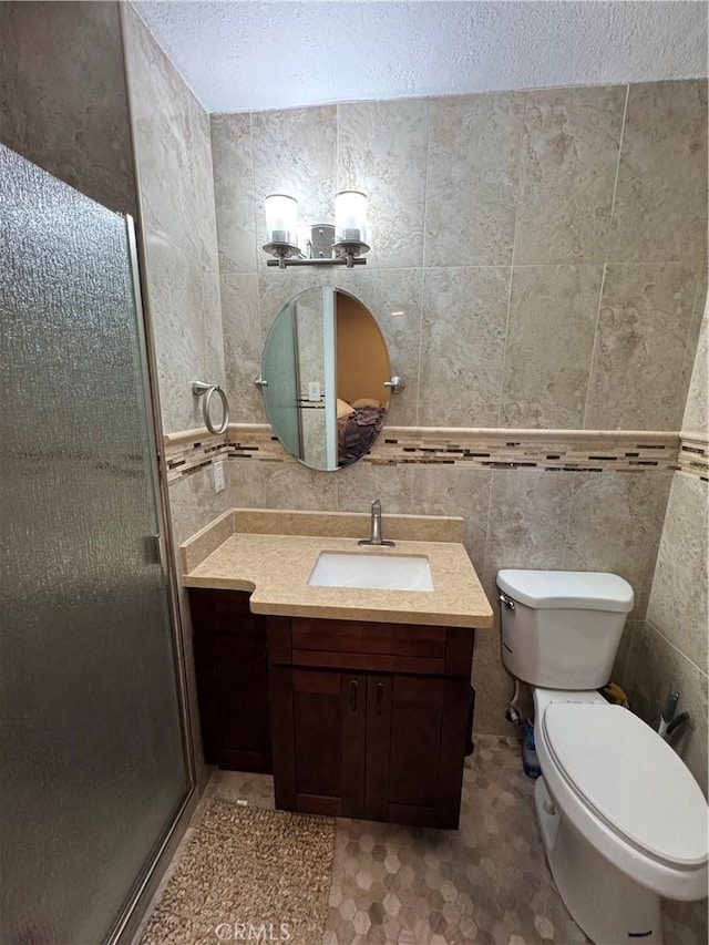 bathroom featuring toilet, a textured ceiling, tile walls, a shower stall, and vanity