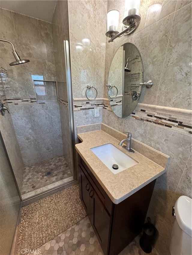 bathroom with vanity, tile walls, toilet, and a shower stall