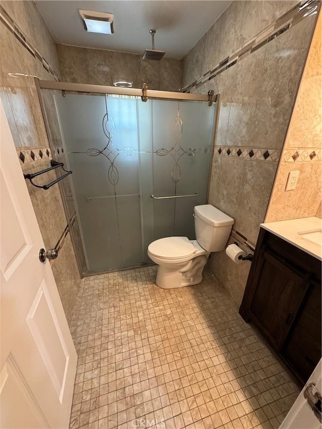 bathroom with toilet, tile walls, a stall shower, and vanity