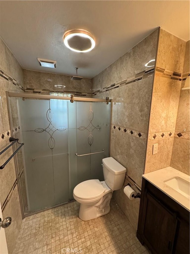 full bathroom featuring vanity, tile walls, toilet, and a stall shower