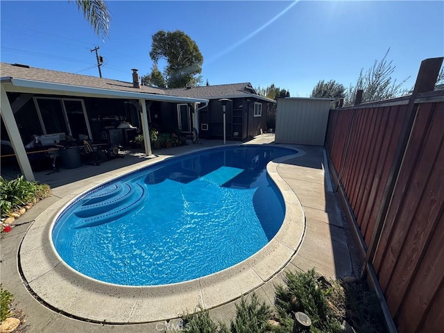 outdoor pool featuring a fenced backyard, a storage shed, an outbuilding, and a patio