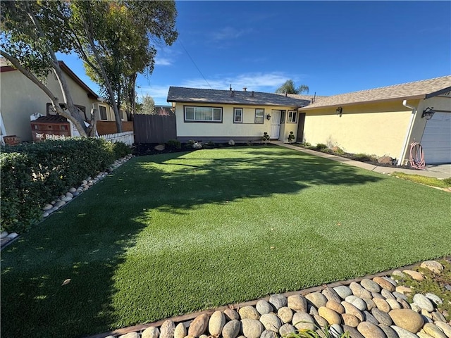 back of house with stucco siding, a lawn, and fence