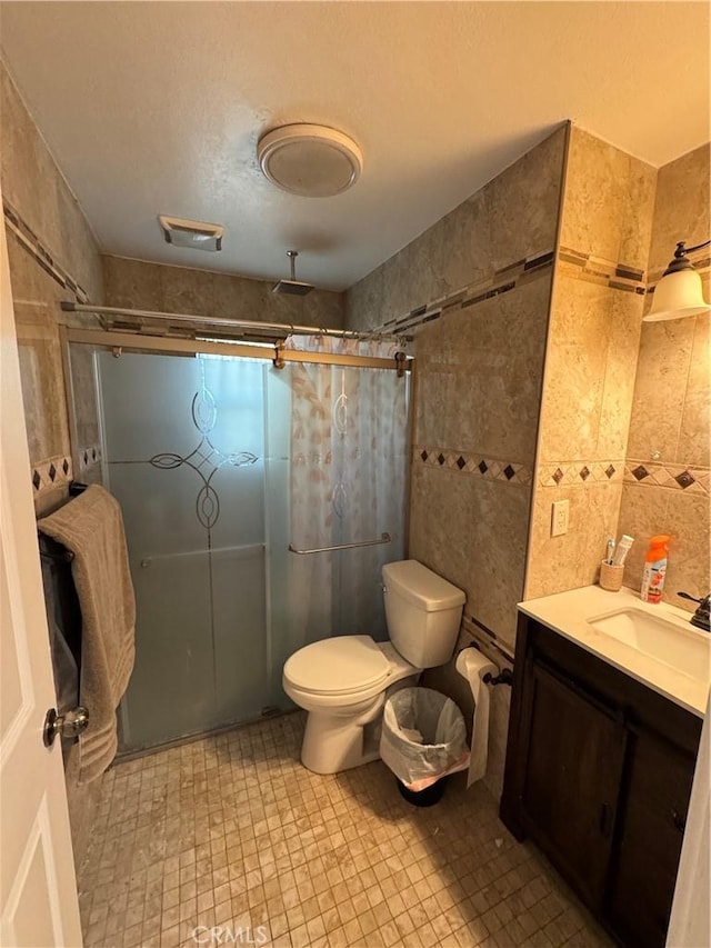 full bathroom featuring visible vents, toilet, tile walls, a shower stall, and vanity