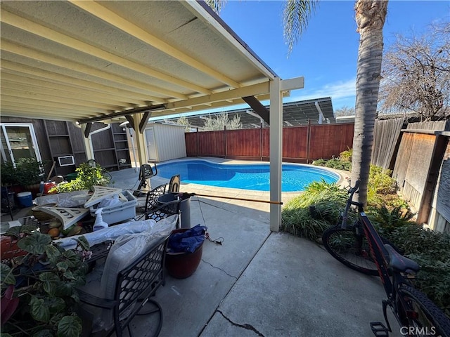 view of swimming pool with a fenced in pool, a storage shed, a fenced backyard, an outbuilding, and a patio