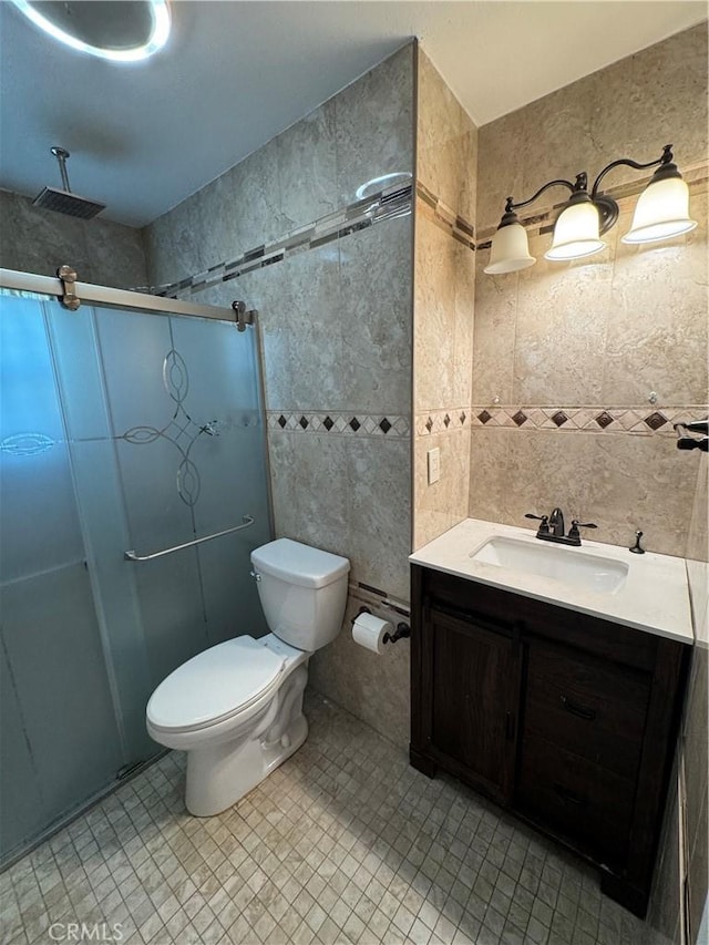 full bathroom with vanity, tile walls, toilet, and a stall shower