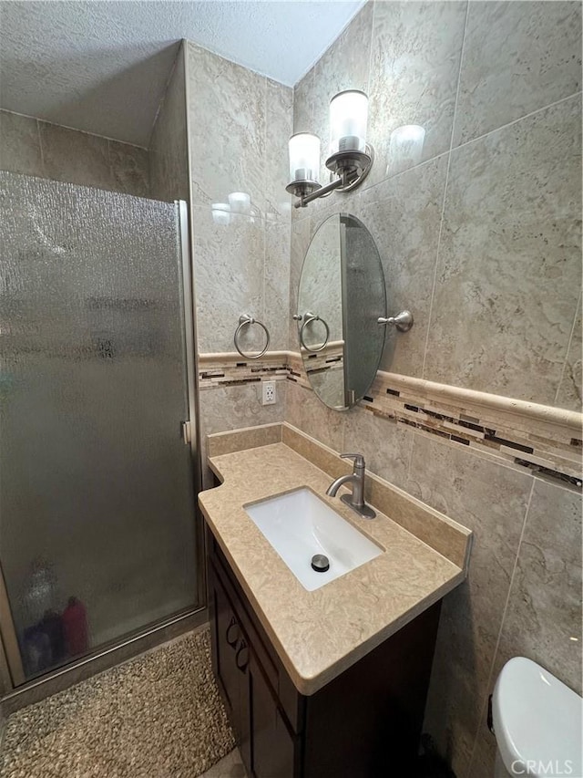 bathroom featuring vanity, tile walls, a stall shower, and a textured ceiling