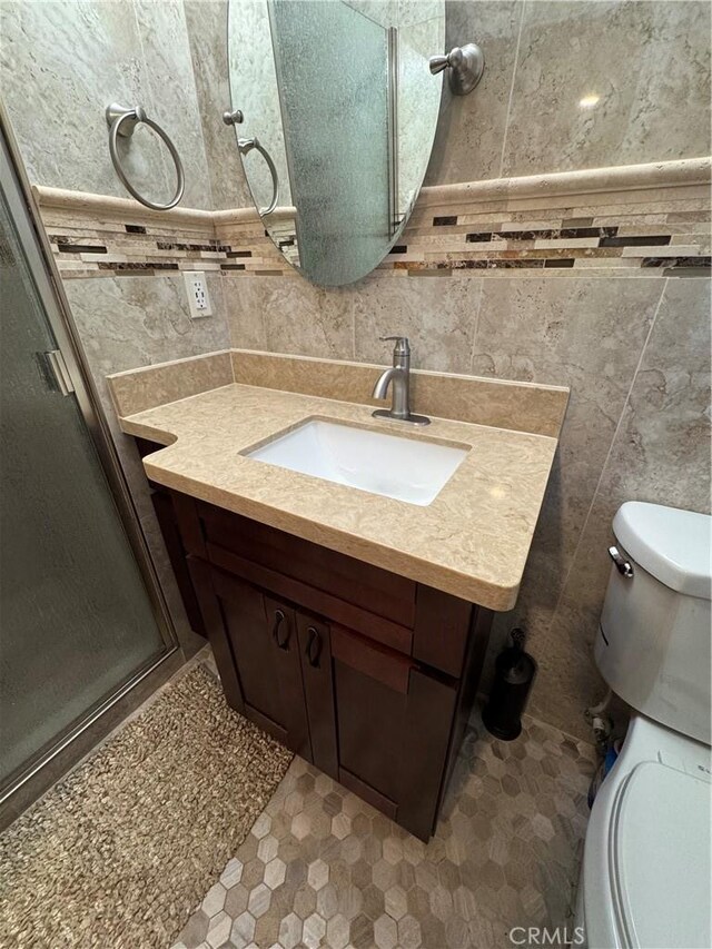 bathroom featuring tile walls, a shower stall, toilet, and vanity