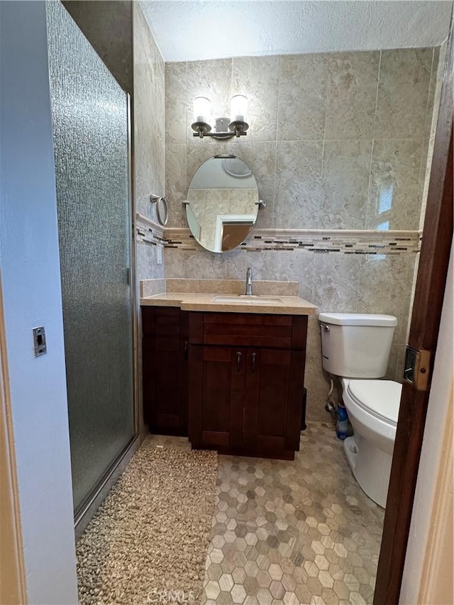 full bath featuring vanity, tile walls, a shower stall, and toilet