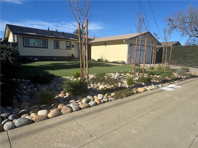 view of front of home with stucco siding, an attached garage, driveway, and a front lawn