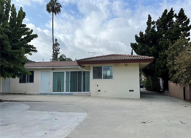 back of property with a tile roof and stucco siding