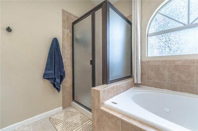 bathroom featuring tile patterned flooring, a shower stall, a garden tub, and baseboards