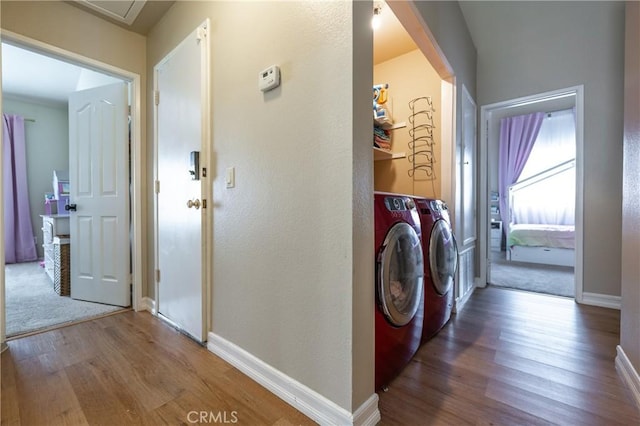 clothes washing area with laundry area, wood finished floors, baseboards, and washing machine and clothes dryer