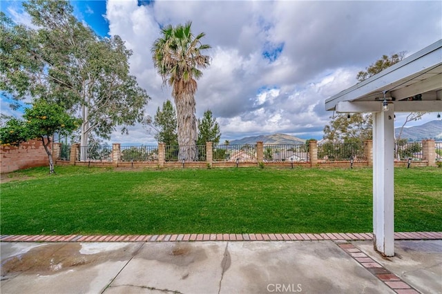 view of yard featuring a patio area, a mountain view, and a fenced backyard