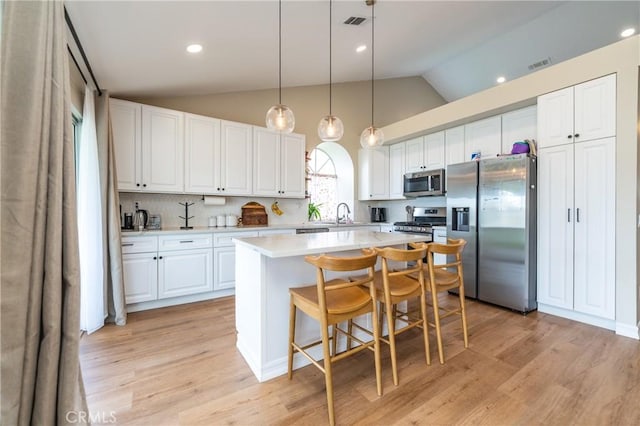 kitchen featuring a kitchen island, white cabinets, stainless steel appliances, and light countertops