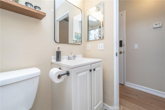 bathroom featuring vanity, toilet, wood finished floors, and baseboards