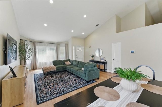 living area featuring visible vents, baseboards, light wood-type flooring, recessed lighting, and high vaulted ceiling