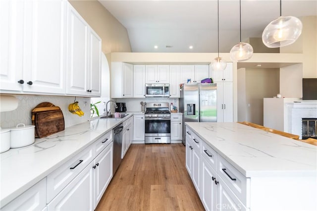 kitchen featuring a kitchen island, appliances with stainless steel finishes, white cabinetry, and a sink