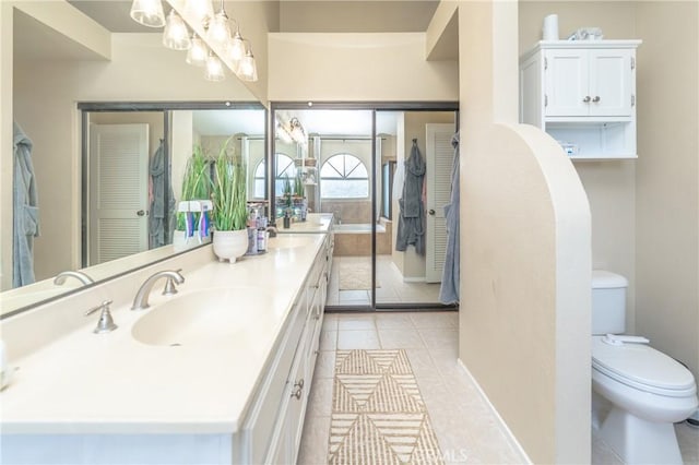 bathroom featuring baseboards, toilet, double vanity, tile patterned floors, and a sink