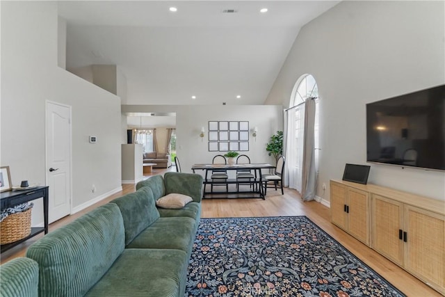 living room featuring light wood-style flooring, recessed lighting, baseboards, and high vaulted ceiling