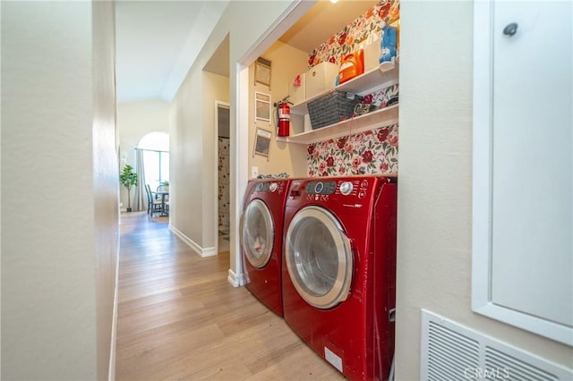 laundry area featuring baseboards, visible vents, light wood finished floors, laundry area, and washer and clothes dryer