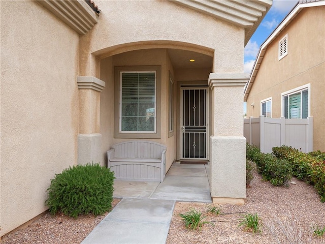 entrance to property with fence and stucco siding