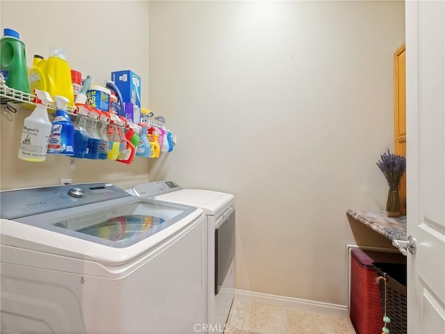 clothes washing area with washer and dryer, baseboards, and laundry area