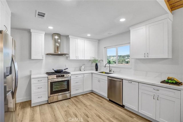 kitchen with visible vents, light wood-style flooring, stainless steel appliances, wall chimney exhaust hood, and a sink