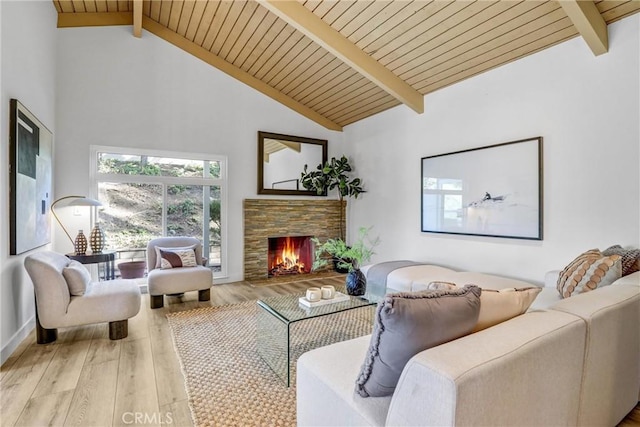 living area with beamed ceiling, wooden ceiling, a stone fireplace, and wood finished floors