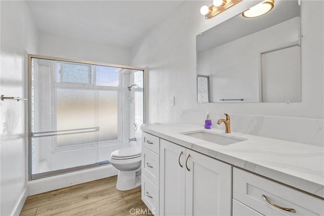 bathroom featuring vanity, toilet, wood finished floors, and a shower stall