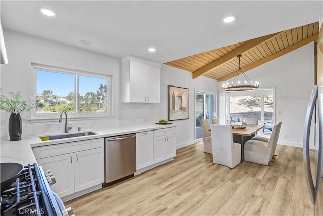 kitchen with a sink, stainless steel appliances, white cabinets, and vaulted ceiling