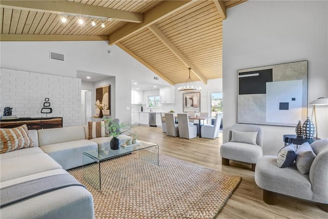 living area with beamed ceiling, a notable chandelier, visible vents, and light wood-type flooring