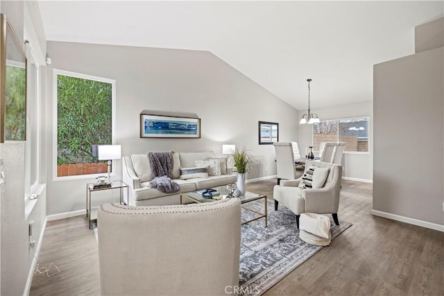 living room with an inviting chandelier, baseboards, lofted ceiling, and wood finished floors