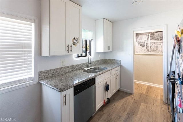 kitchen with stainless steel dishwasher, white cabinets, light wood-type flooring, and a sink