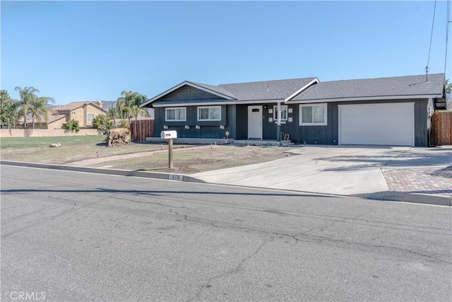 ranch-style house featuring an attached garage, driveway, and fence