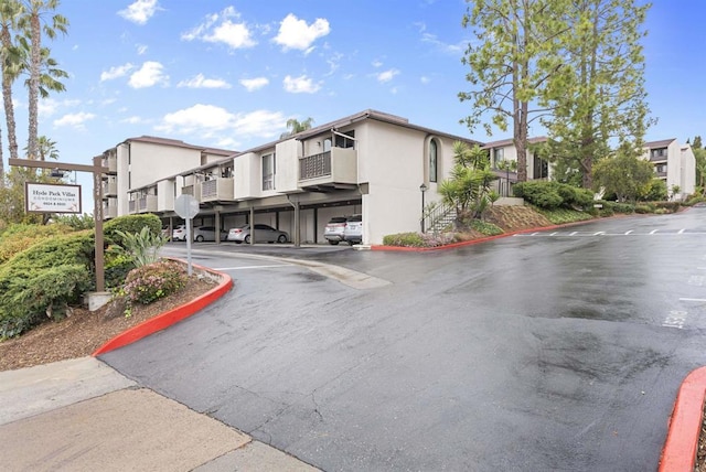 view of building exterior with covered and uncovered parking and a residential view