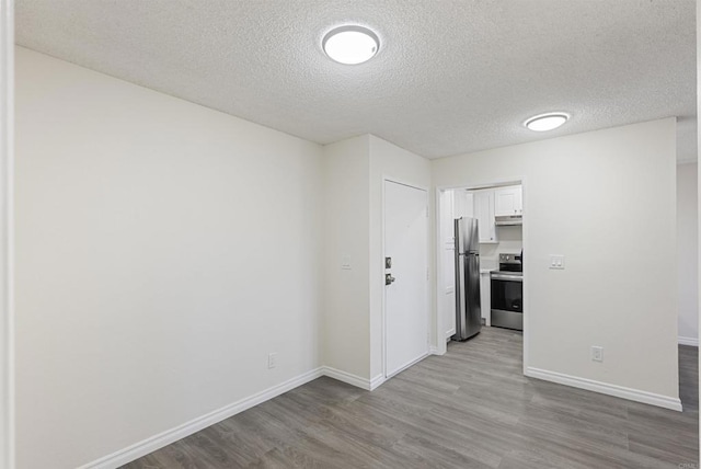 unfurnished room with baseboards, a textured ceiling, and wood finished floors