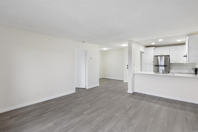 unfurnished living room with baseboards, recessed lighting, a sink, dark wood-type flooring, and a textured ceiling