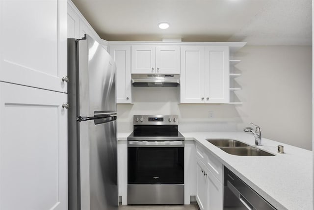 kitchen featuring under cabinet range hood, light countertops, appliances with stainless steel finishes, white cabinets, and a sink