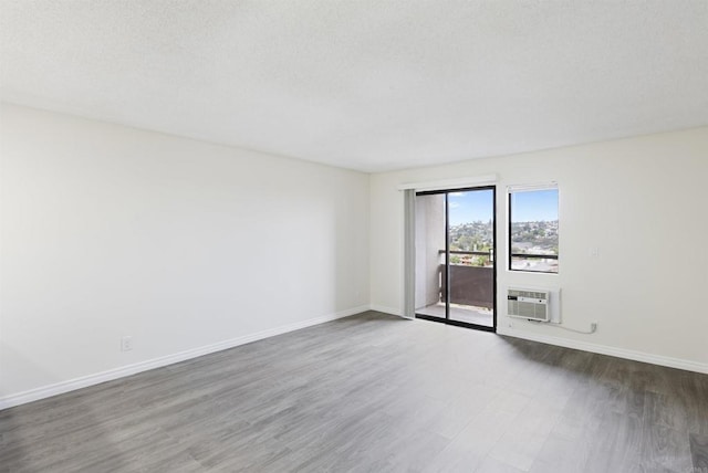 unfurnished room with wood finished floors, baseboards, and a textured ceiling